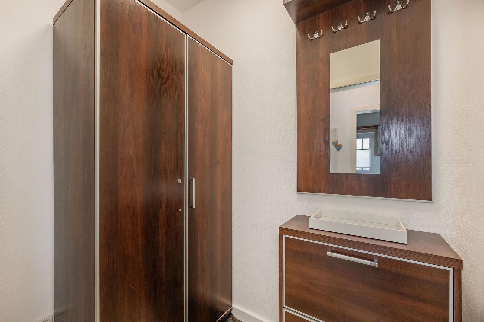 Cabinet and sink with mirror and hook wall in the bathroom.