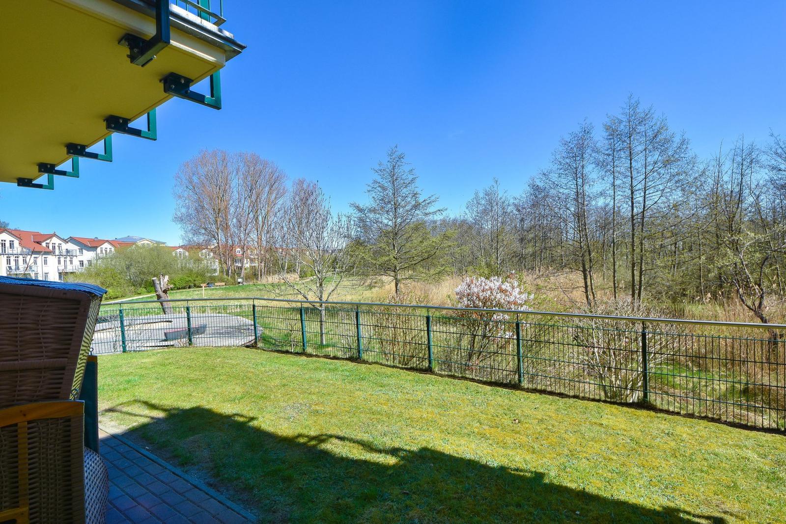 Terrace with view of green area and trees under blue sky.