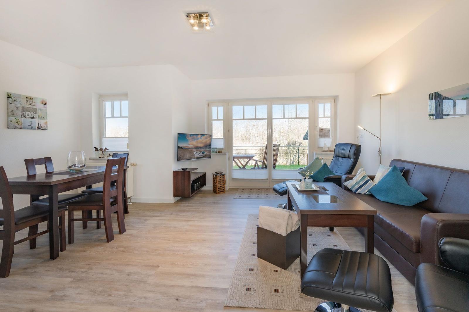 Living and dining area with sofa, dining table, and TV. Access to terrace.