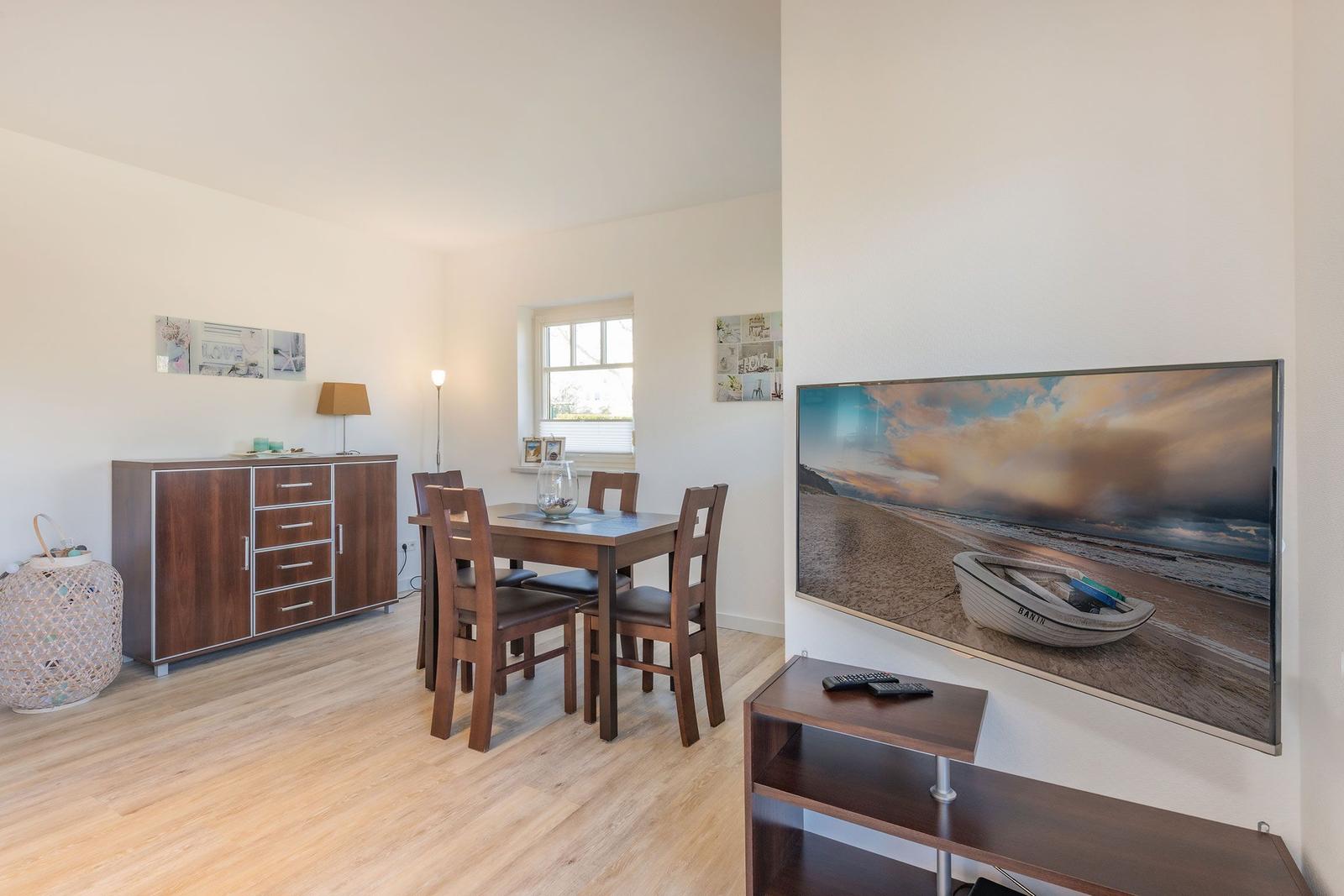 Dining room with wooden table, chairs, and TV on the wall.