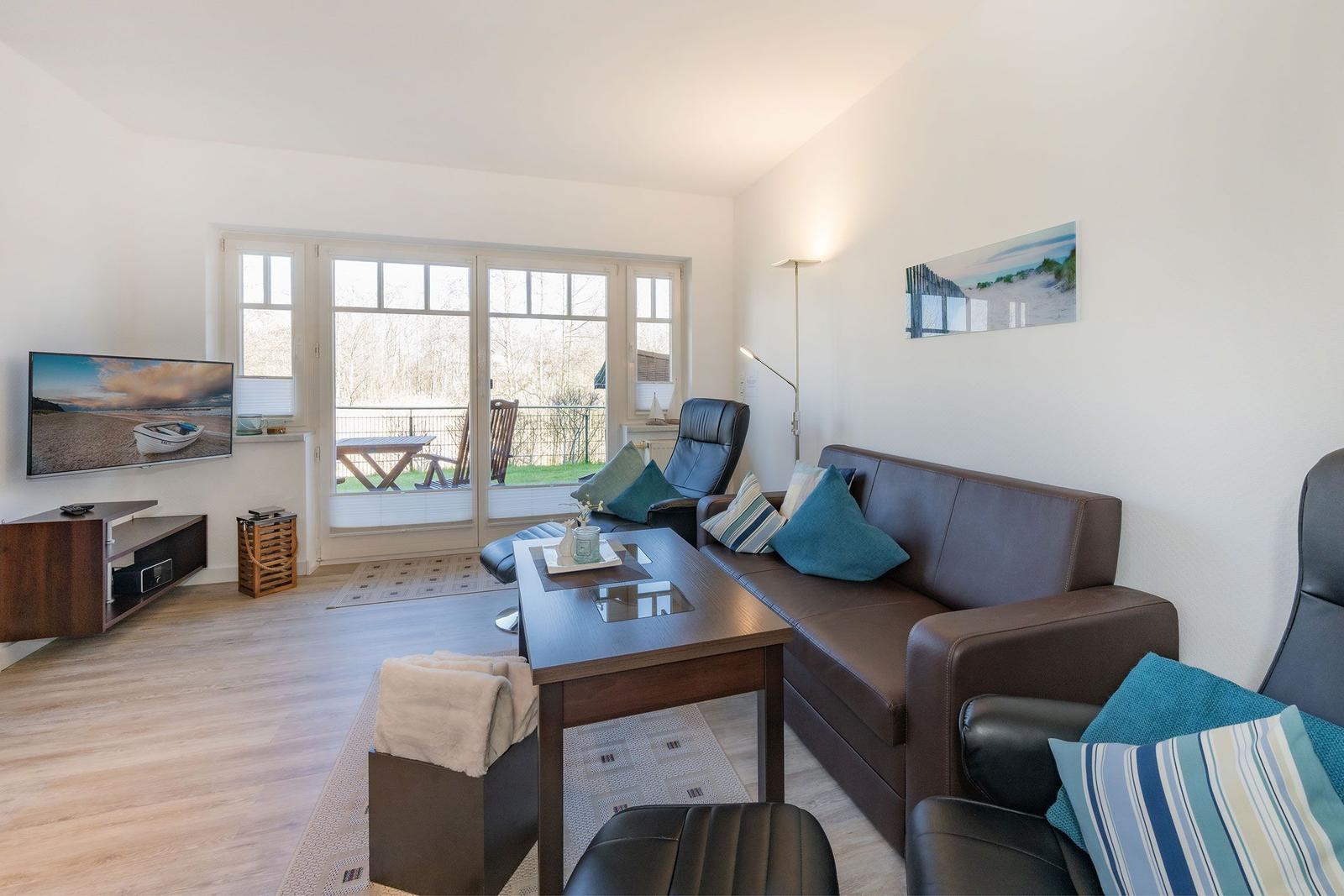 Living room with sofa, coffee table, and TV. Entrance to terrace with garden view.