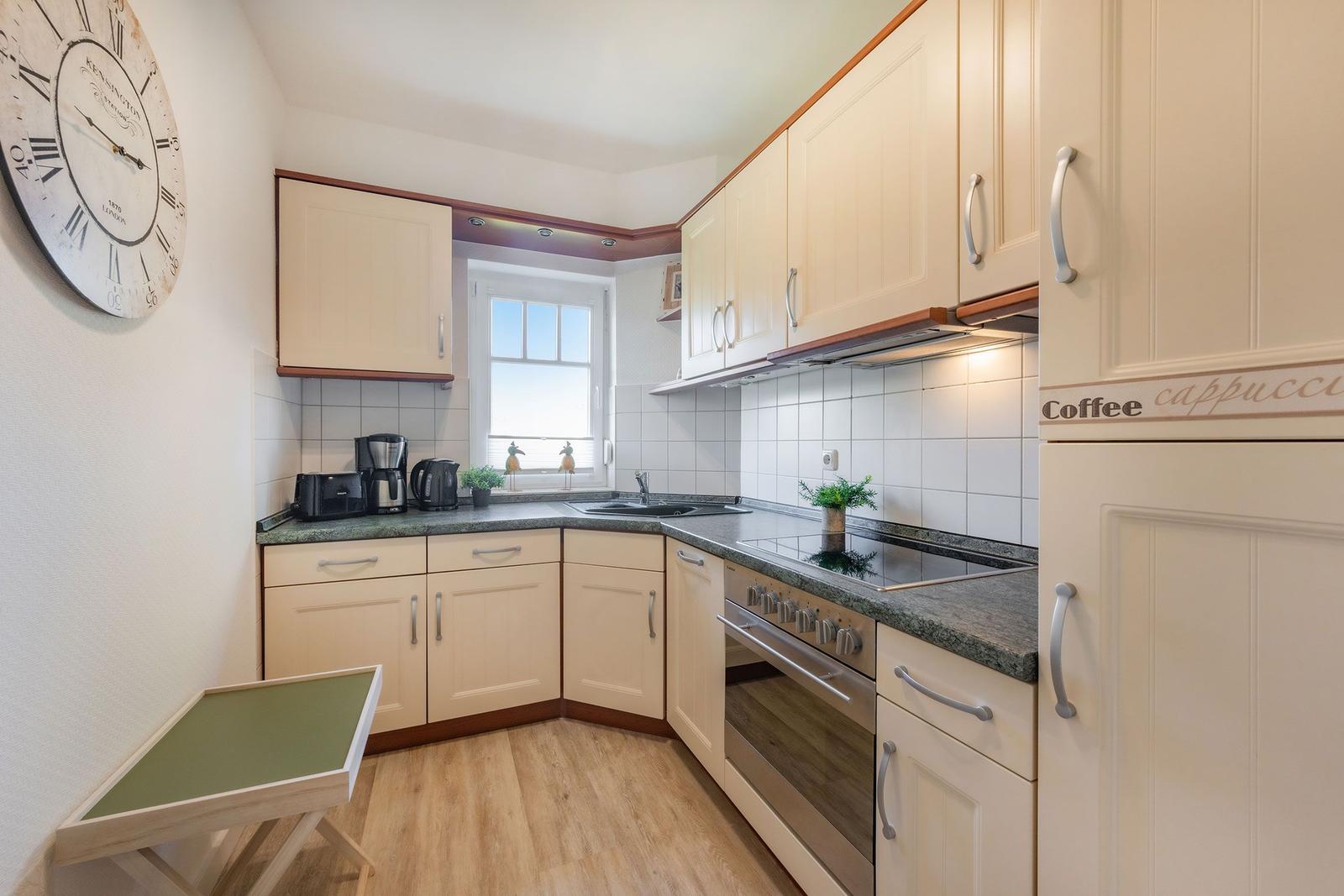 Kitchen with light cabinets, countertop, and window.