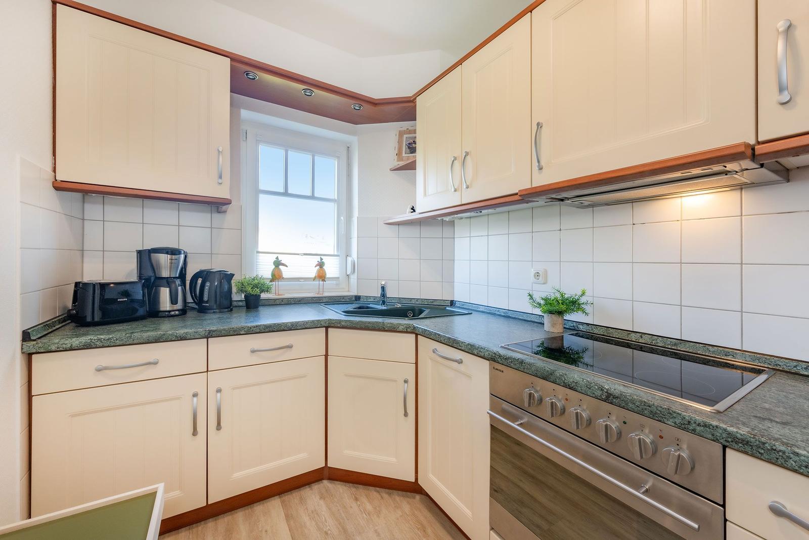 Kitchen with light cabinets, granite countertop, and window. Stove and sink are present.