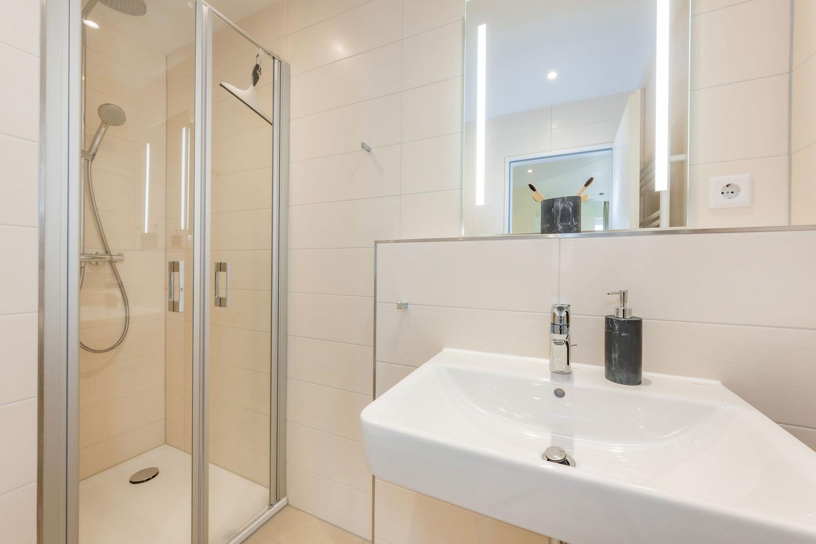 Bad mit Dusche und Waschbecken mit Spiegel