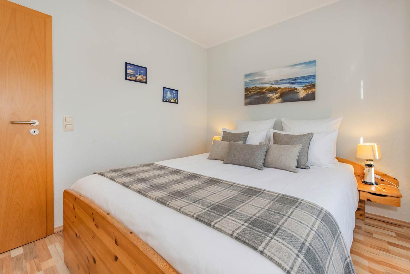 Schlafzimmer mit Bett, Holzfußboden und Wandbildern.