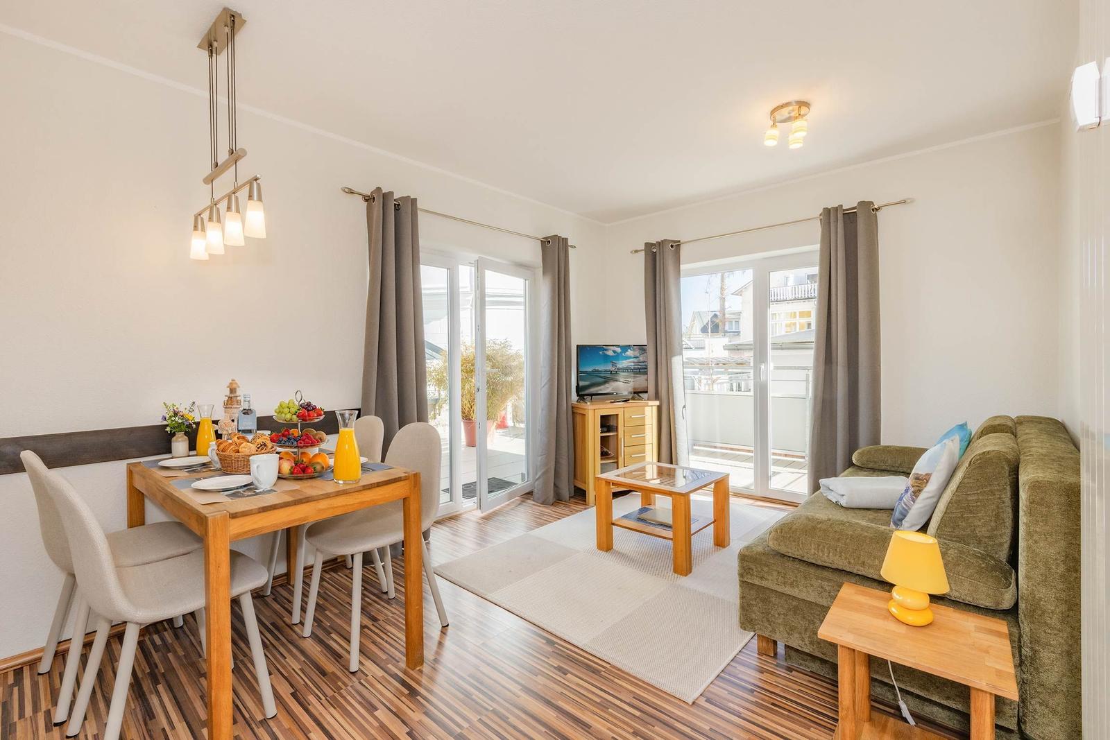 Wohn- und Essbereich mit Sofa, Esstisch und Blick auf Balkon.