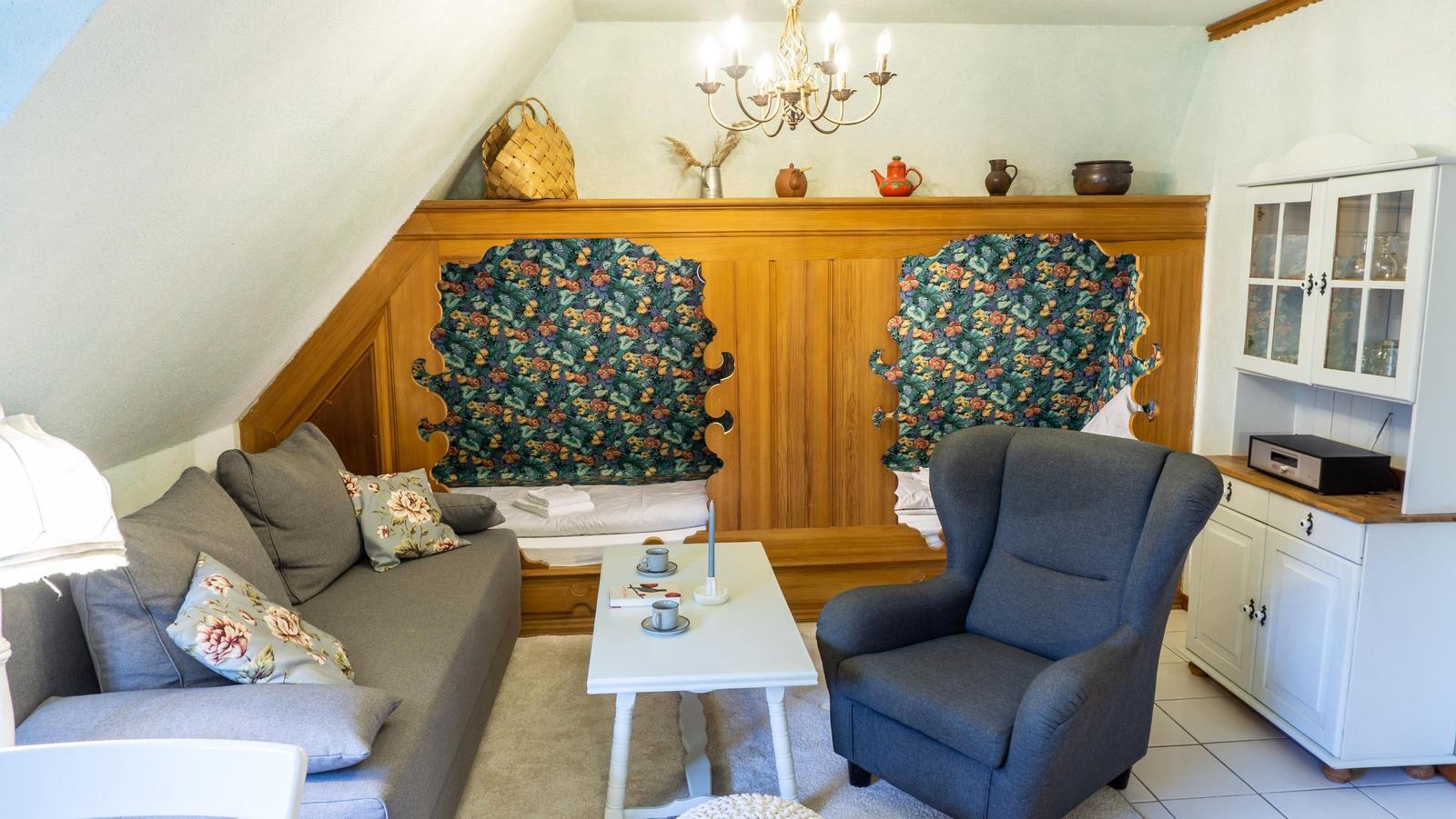 Wohnzimmer mit Sofa, Sessel und Holzpaneelen an der Wand.