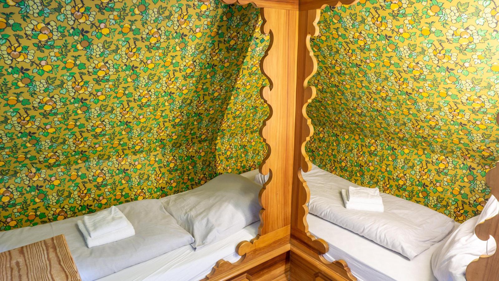 Zwei Betten unter einem Holzbettgestell mit gemusterten Wänden.