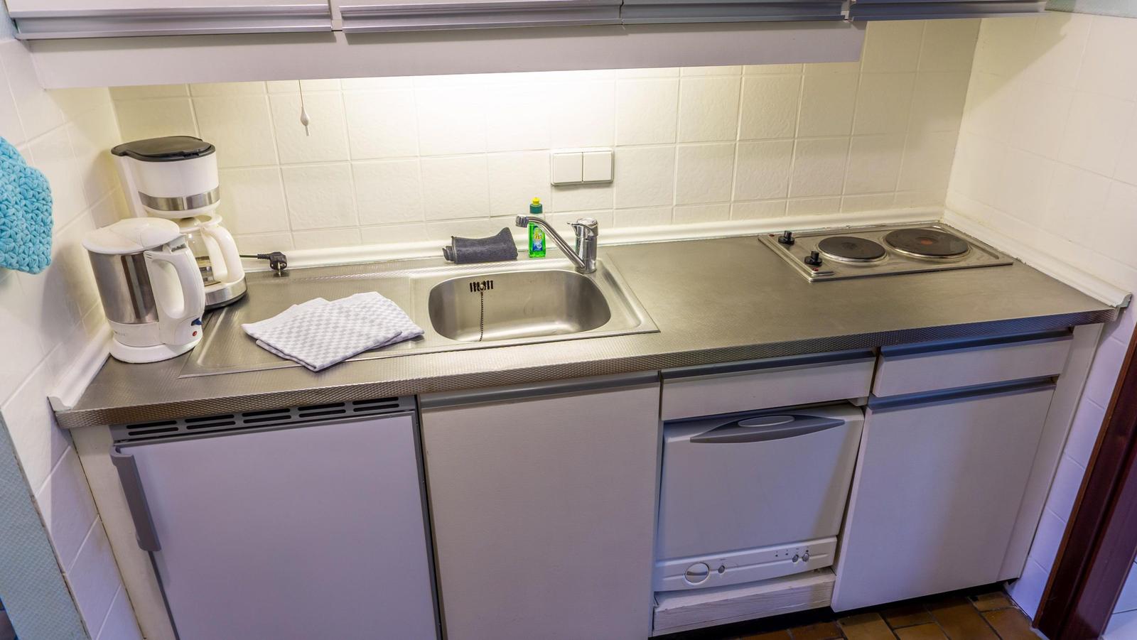 Küche mit Spüle, Herd, Kaffeemaschine und Wasserkocher.