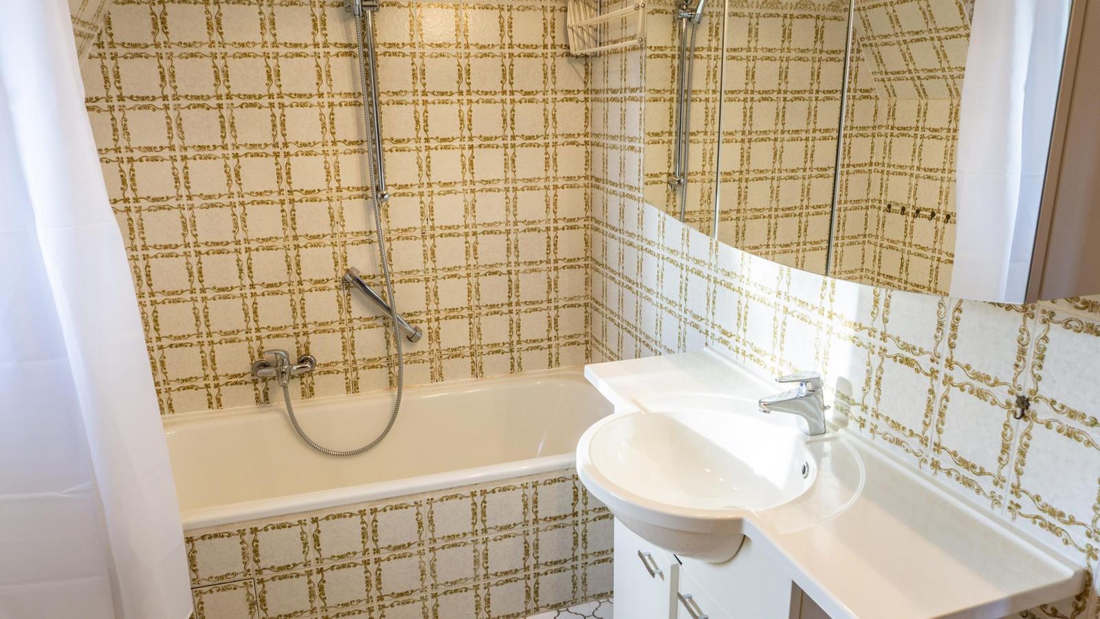 Badezimmer mit Badewanne, Dusche und Waschbecken mit Spiegel
