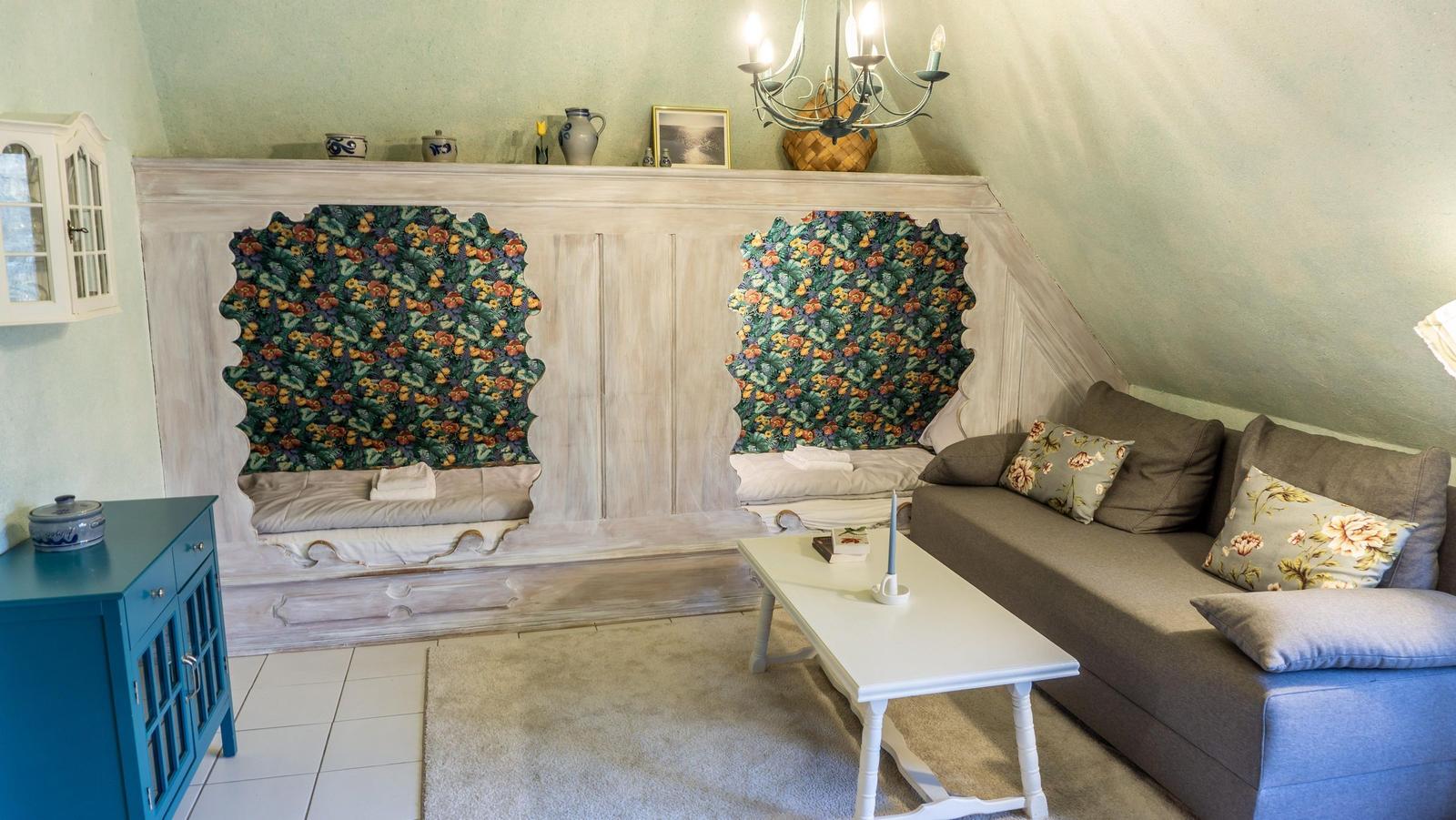 Wohnzimmer mit Sofa, Couchtisch und dekorativen Wandpaneelen mit floraler Tapete.