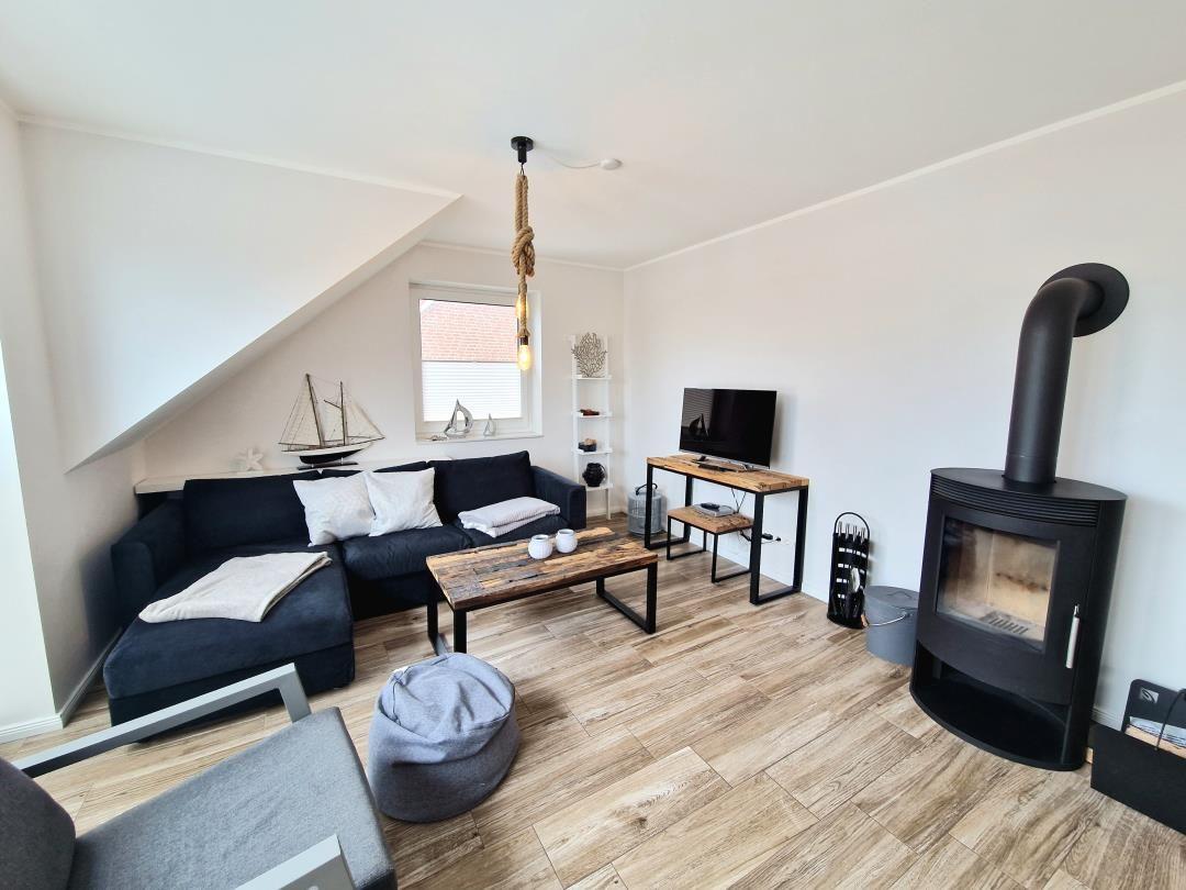 Wohnzimmer mit Sofa, Kamin, TV und Holzboden