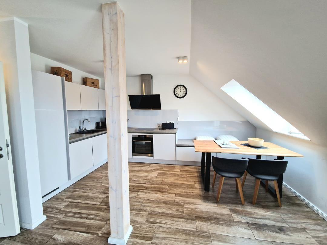 Küche mit Essbereich unter Dachschräge, Holzboden und schlichter Einrichtung.