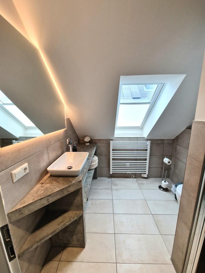 Badezimmer mit Dachschrägen, Waschbecken, Heizkörper und Dachfenster.
