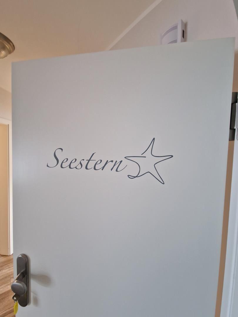 Tür mit Aufschrift Seestern und Sternsymbol. Moderne, schlichte Tür mit Griff.