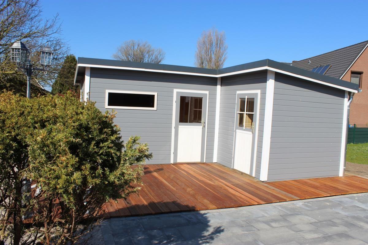 Ein graues Ferienhaus mit weißer Tür und Holzterrasse im Freien.