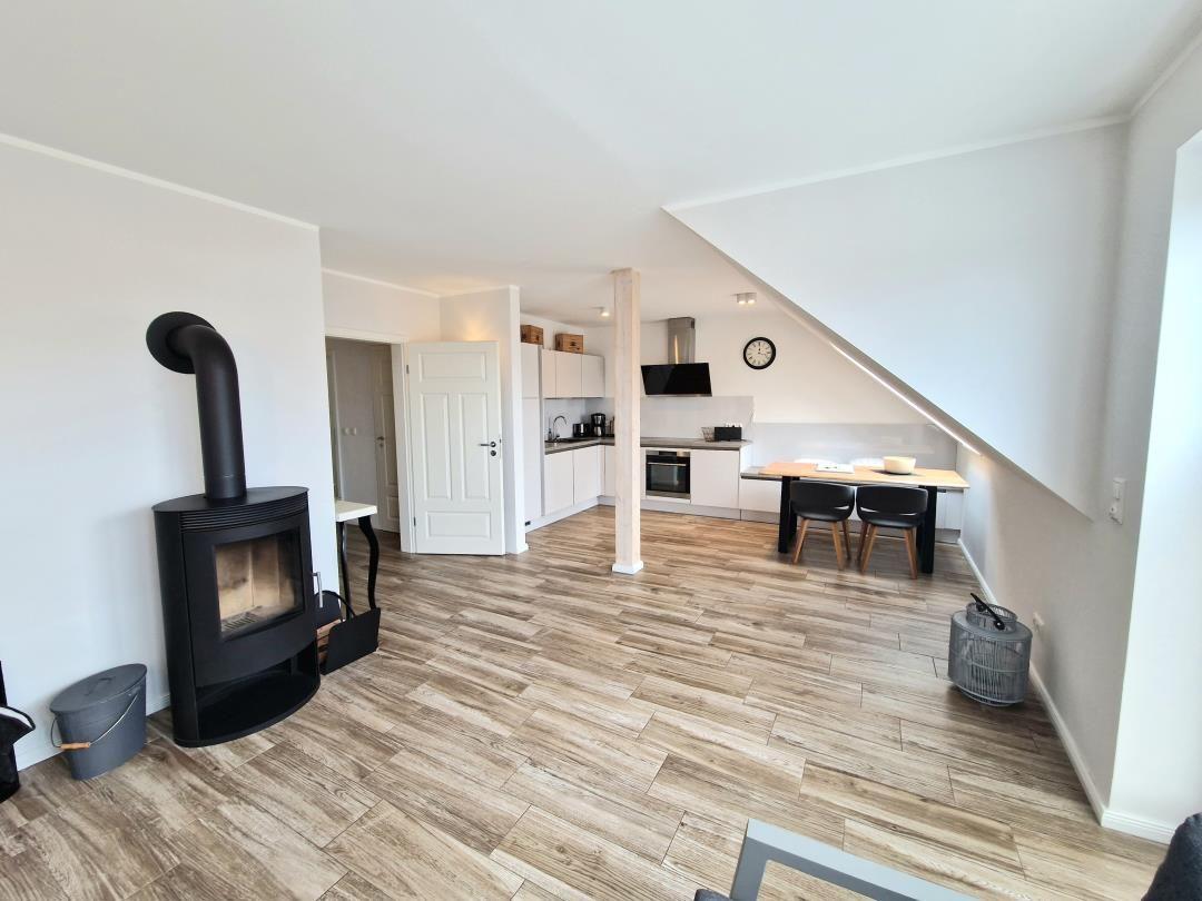 Wohnung mit Holzfußboden, Kaminofen, Küche und Esstisch unter Dachschrägen.