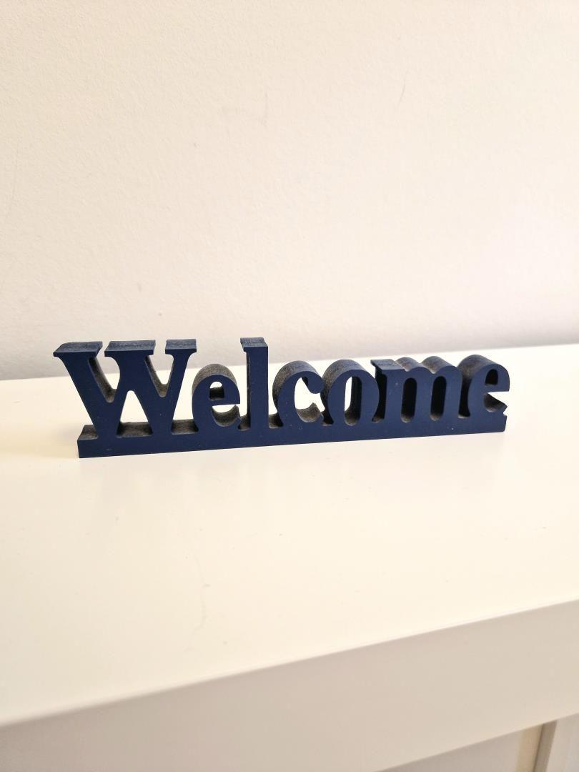 Ein dunkelblaues Welcome-Schild steht auf einer weißen Oberfläche.