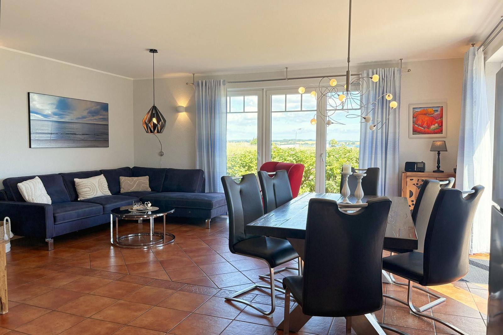Wohn- und Essbereich mit Sofa, Esstisch und Blick auf die Landschaft.