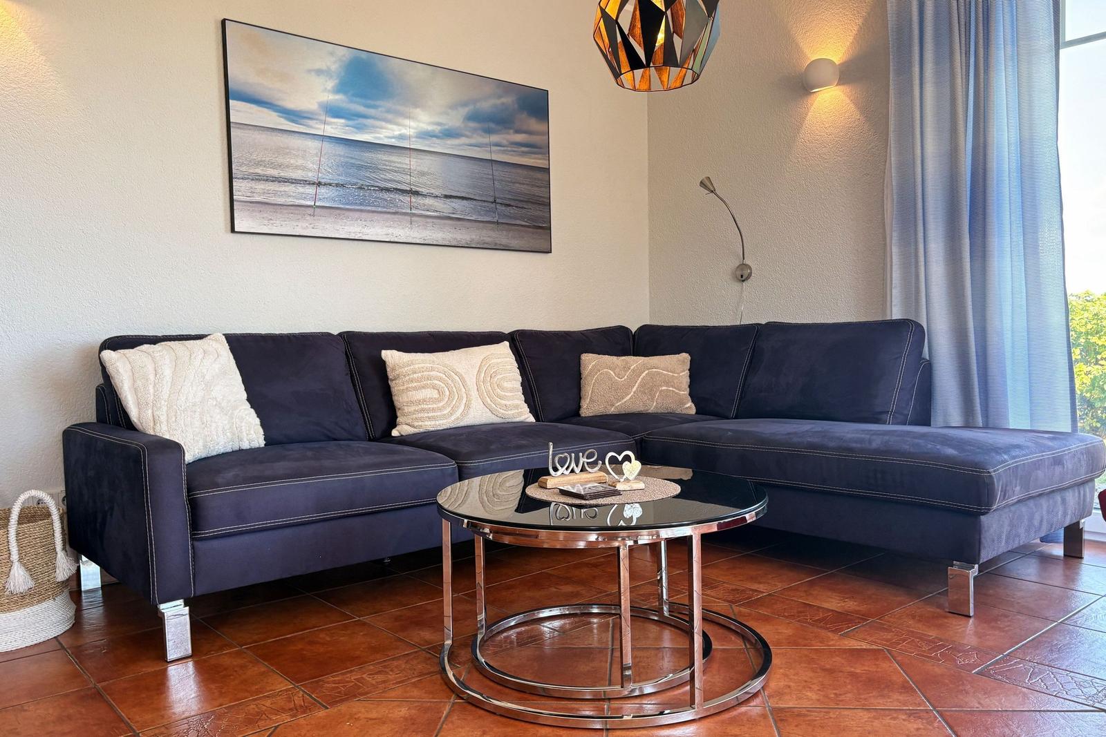 Ein Wohnzimmer mit einem dunkelblauen Sofa, einem runden Tisch und einer Wanddekoration.