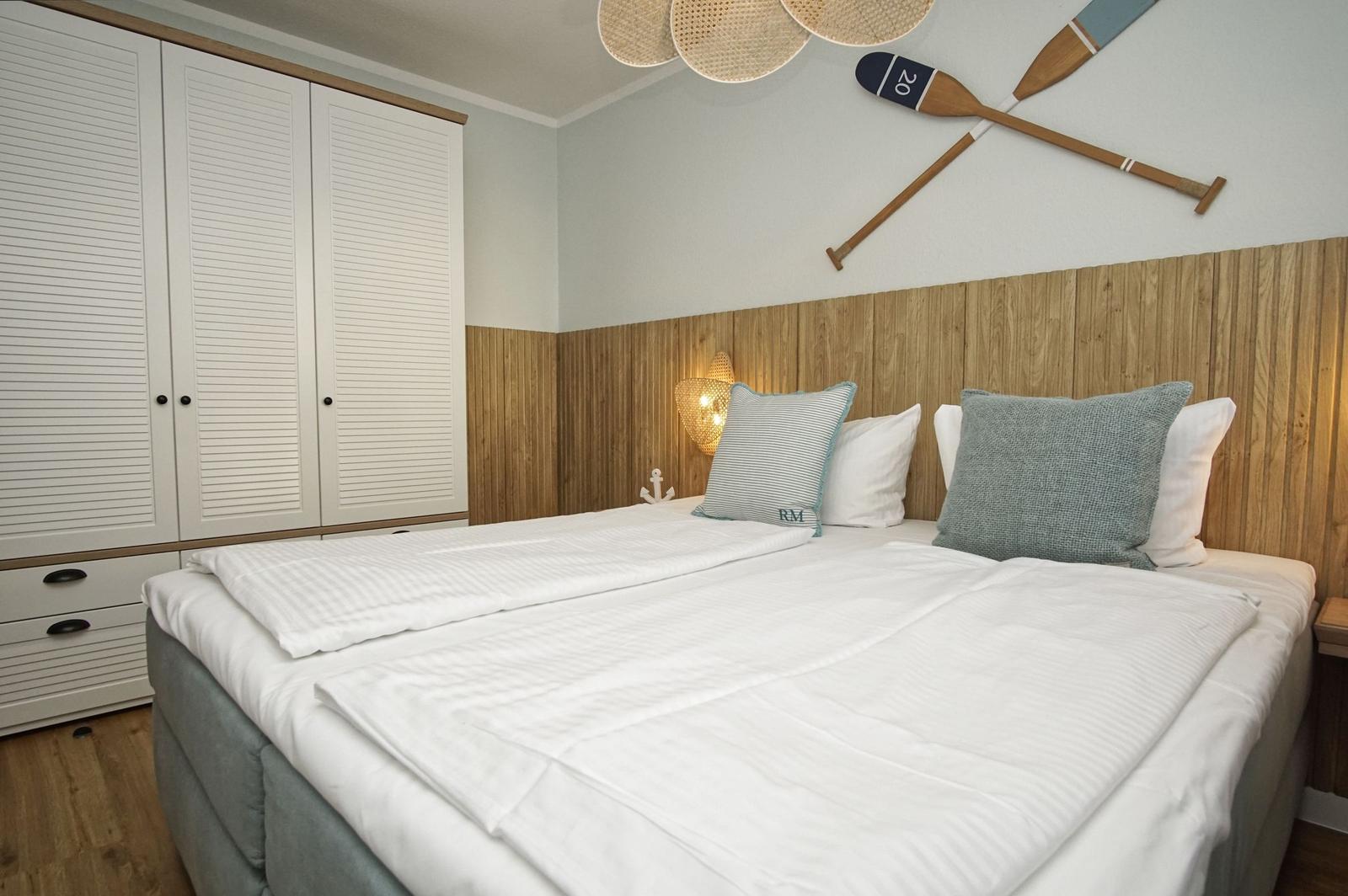 Schlafzimmer mit Bett, Kleiderschrank und Wanddekoration