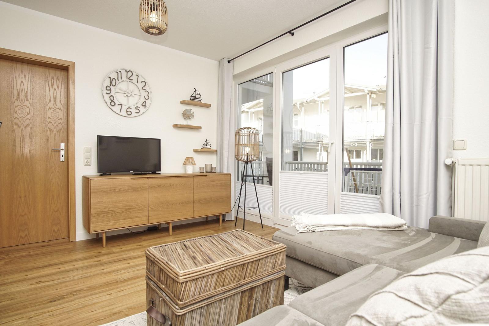 Wohnzimmer mit Sofa, Fernseher und Glasfront zur Terrasse.