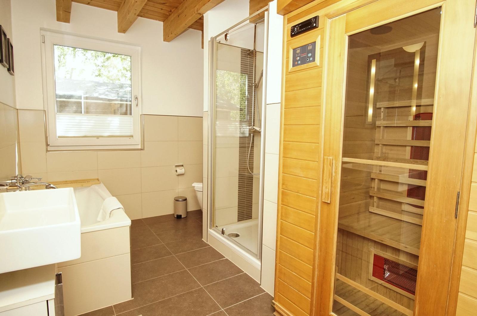 Bathroom with shower, sauna, and bathtub. Wooden ceiling and window.