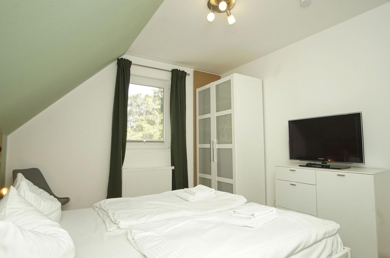Bedroom with double bed, window, wardrobe, and TV.