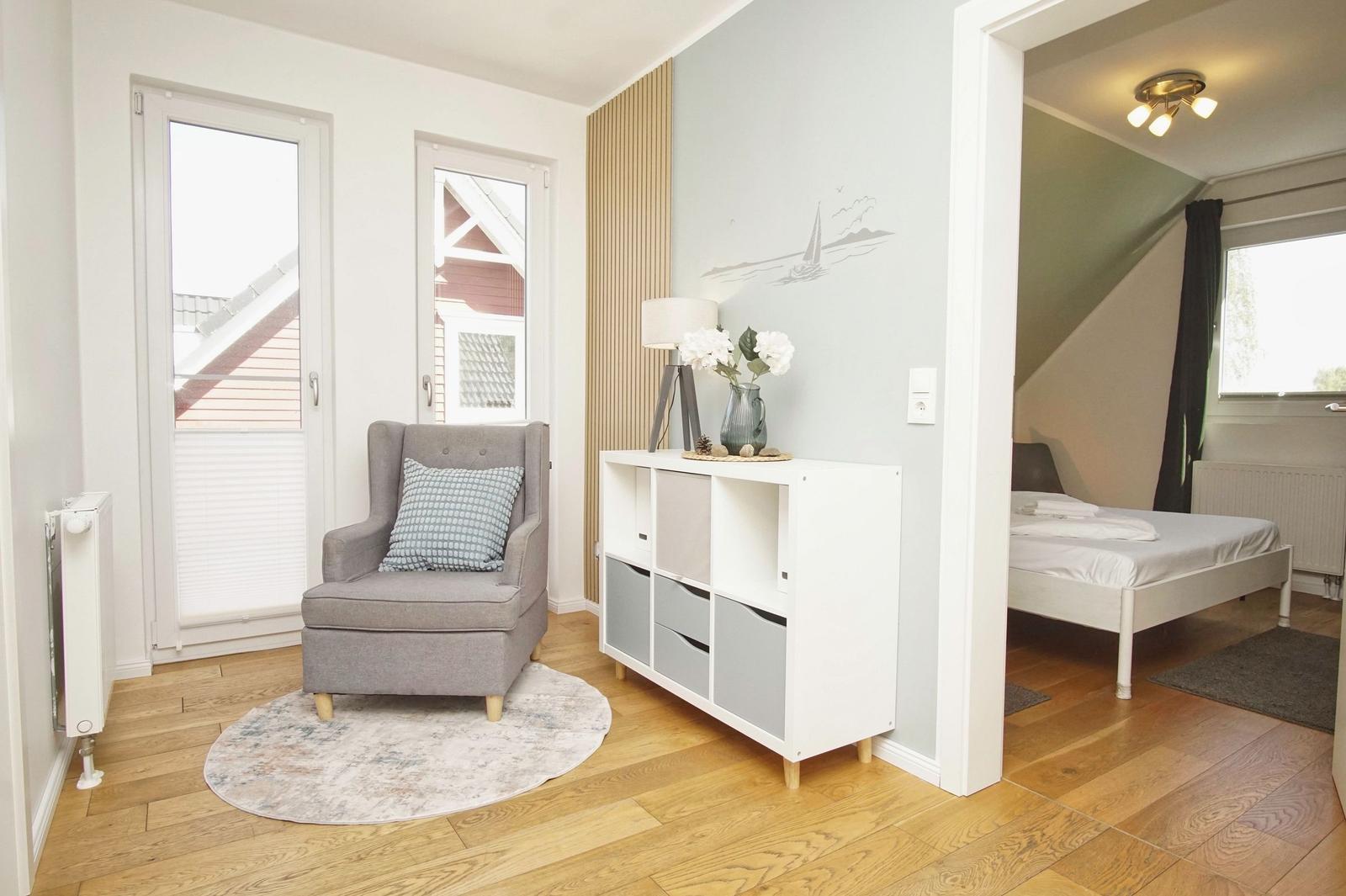 A room with seating area and view of the roof. Passage to bedroom with bed.