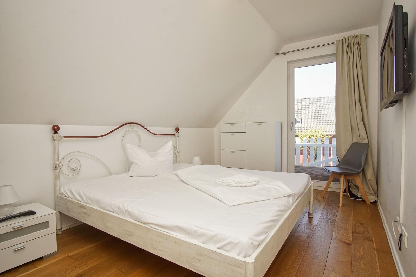 Bedroom with double bed, wardrobe, and TV. Wooden floor and window to terrace.