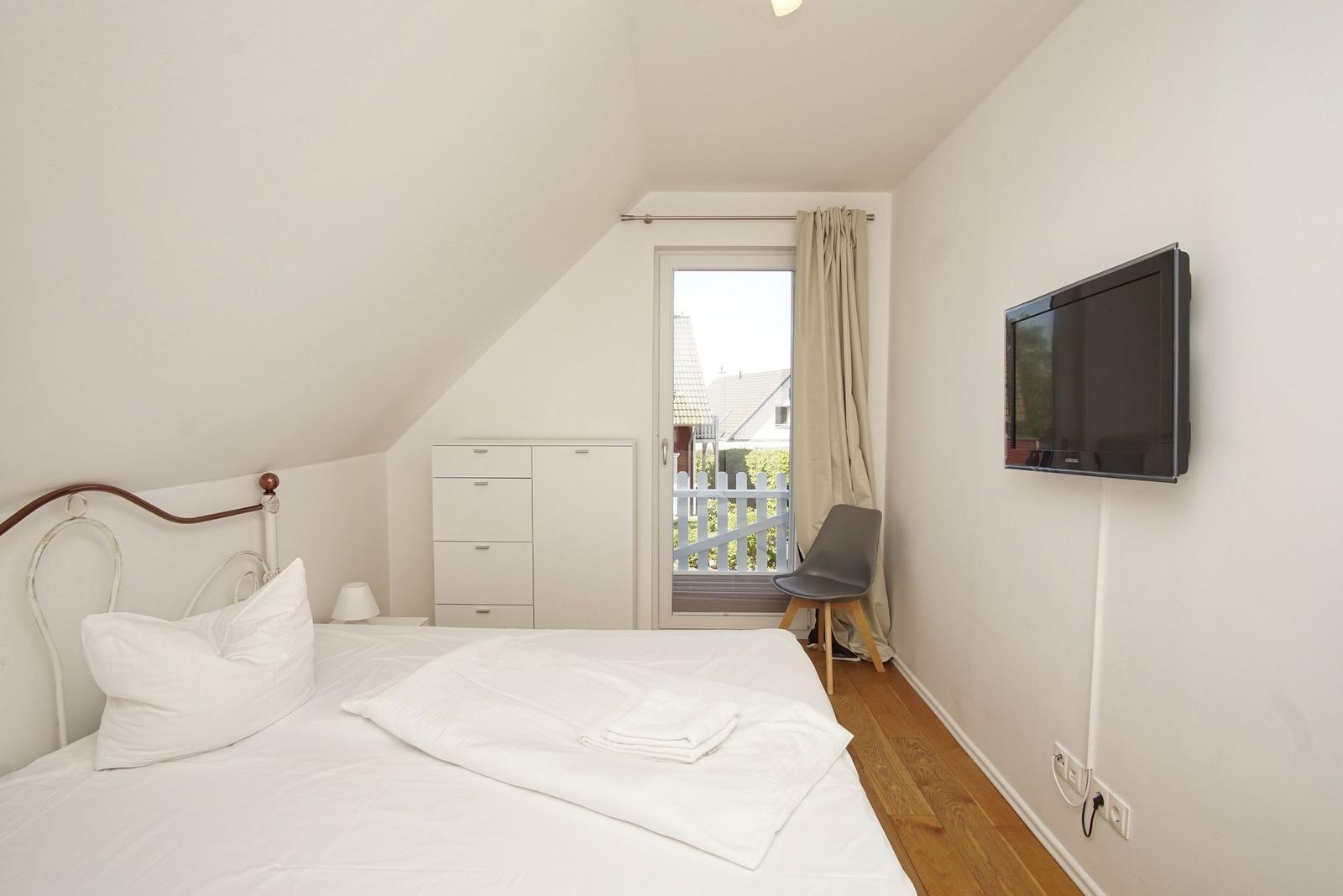 Bedroom with bed, wardrobe, TV, and balcony door.