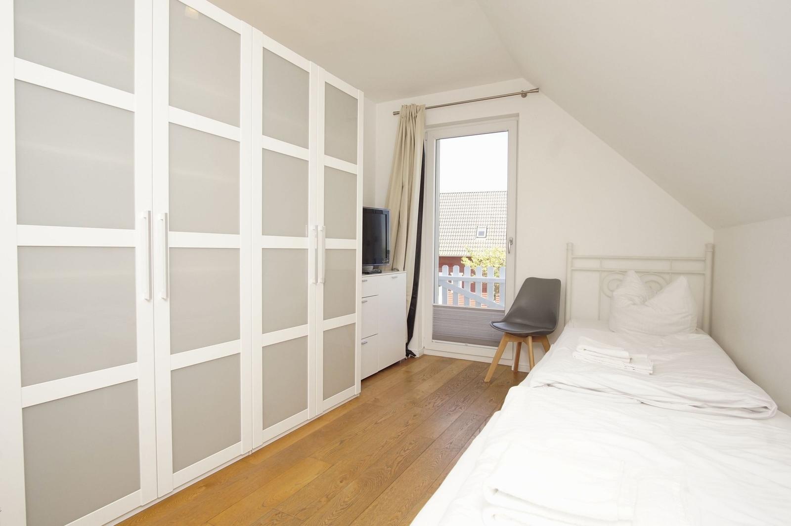 Bedroom with double bed, wardrobe, and balcony door.