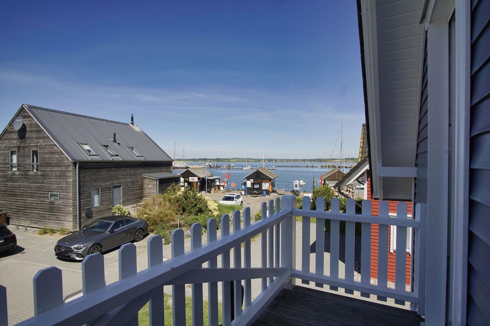 View from balcony over harbor with boats and adjacent buildings.