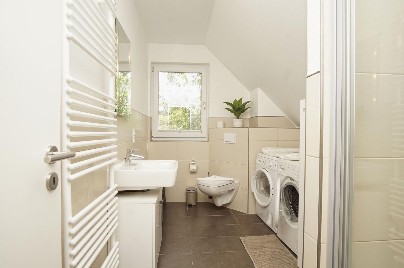Bathroom with washing machine, toilet, and window.