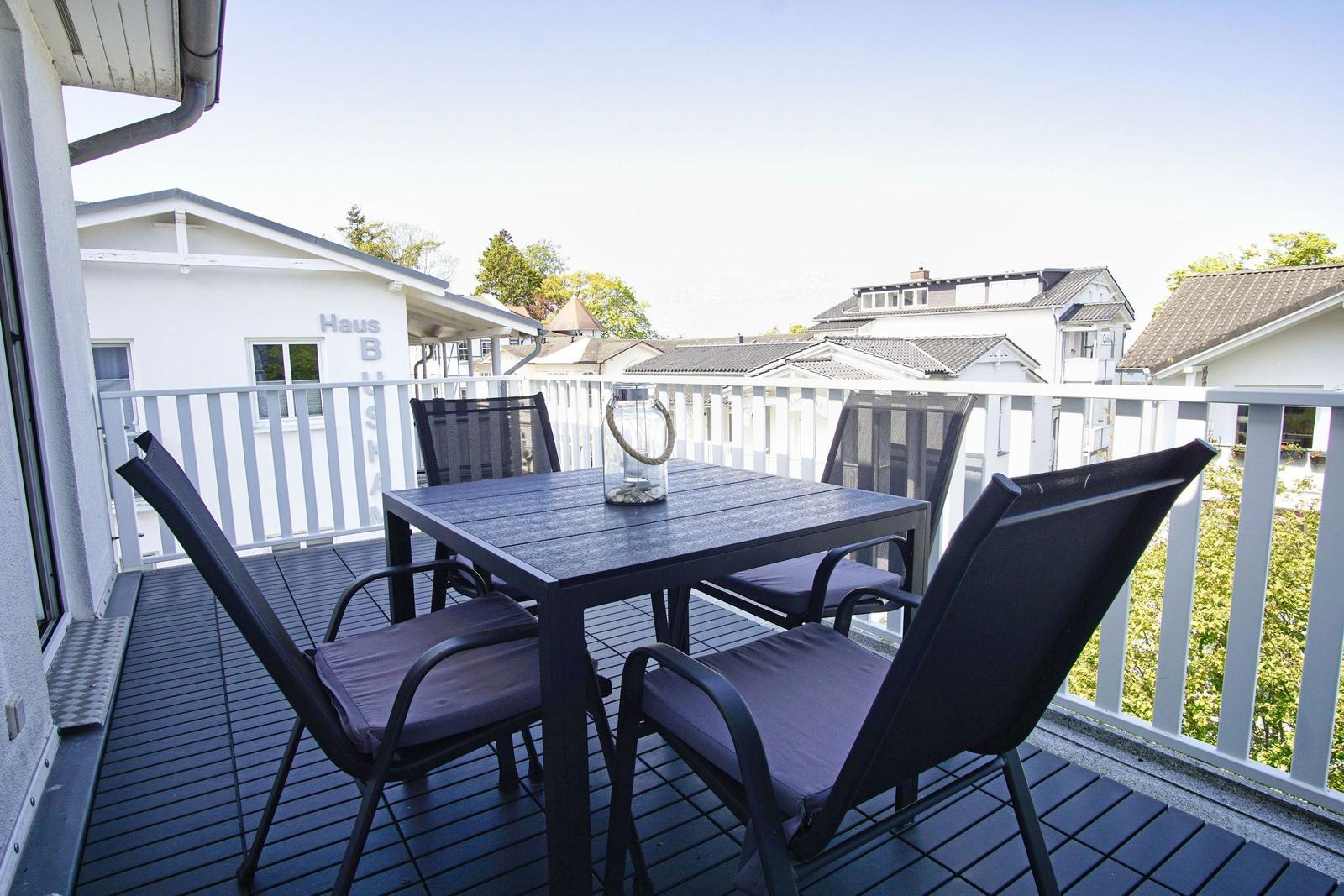 Terrasse mit Tisch und vier Stühlen, Blick auf umliegende Häuser.