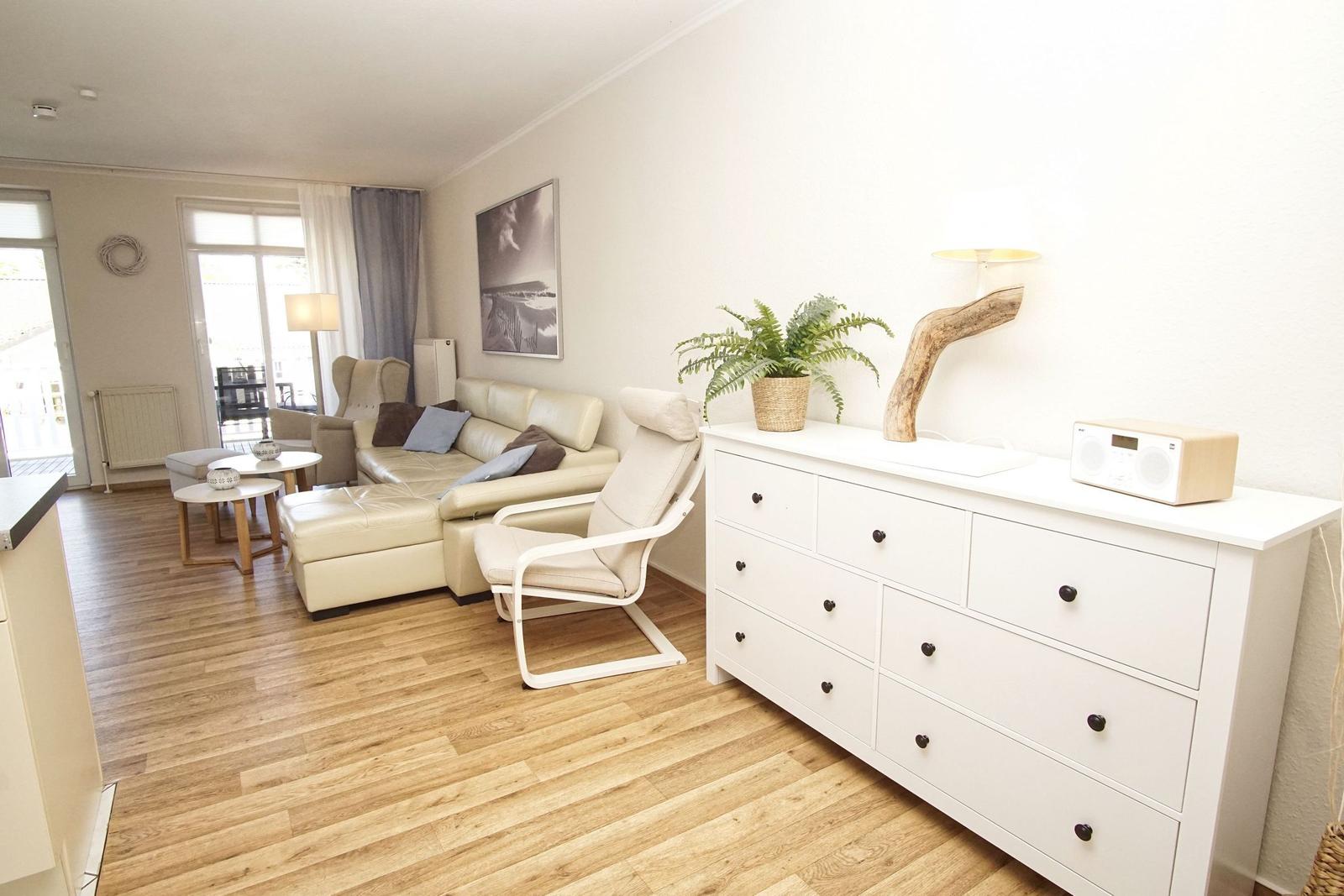 Wohnzimmer mit Sofa, Sessel und Schrank. Holzboden und Fenster mit Blick.