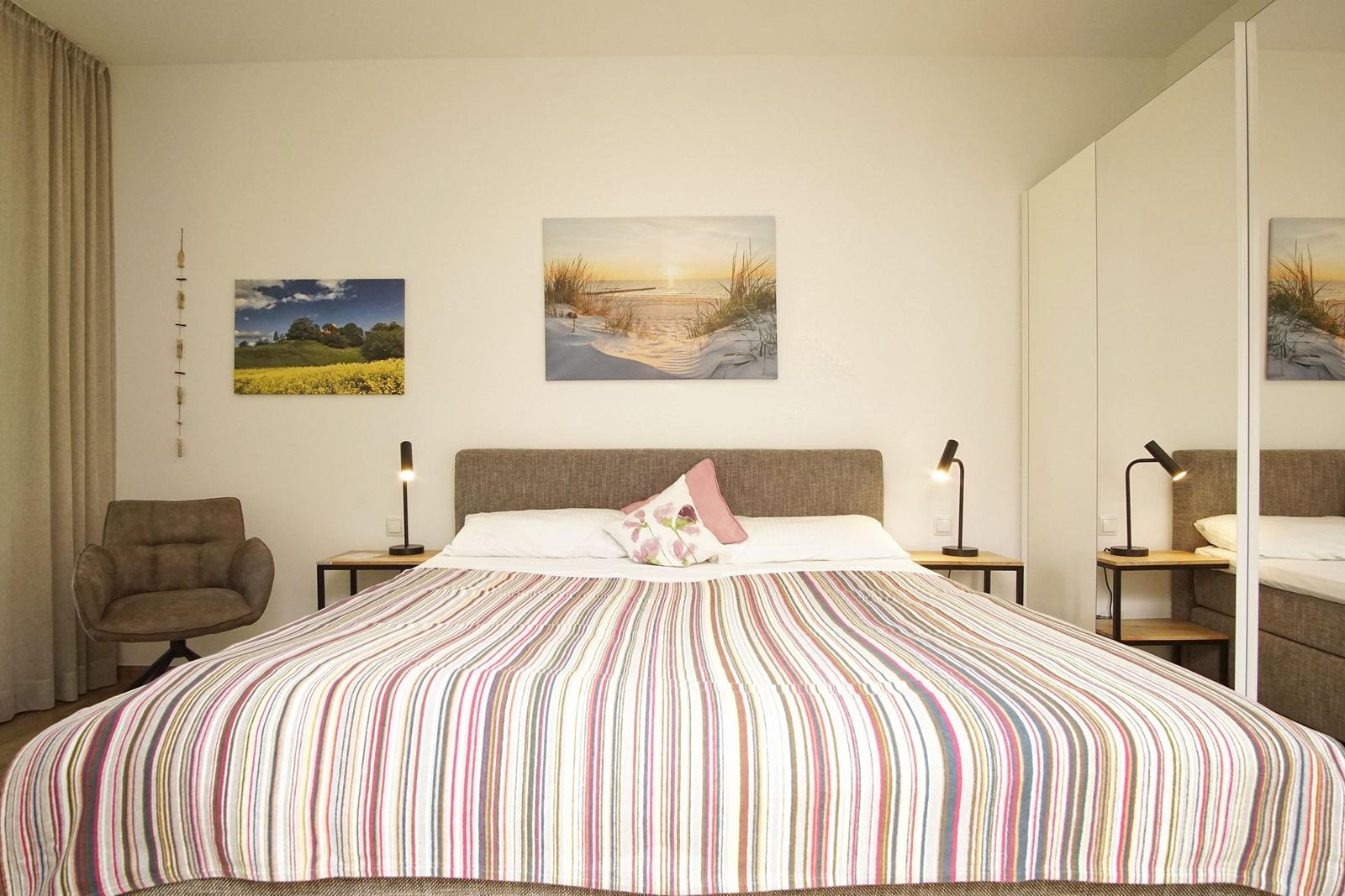 Schlafzimmer mit großem Bett, zwei Nachttischen und Wandbildern.