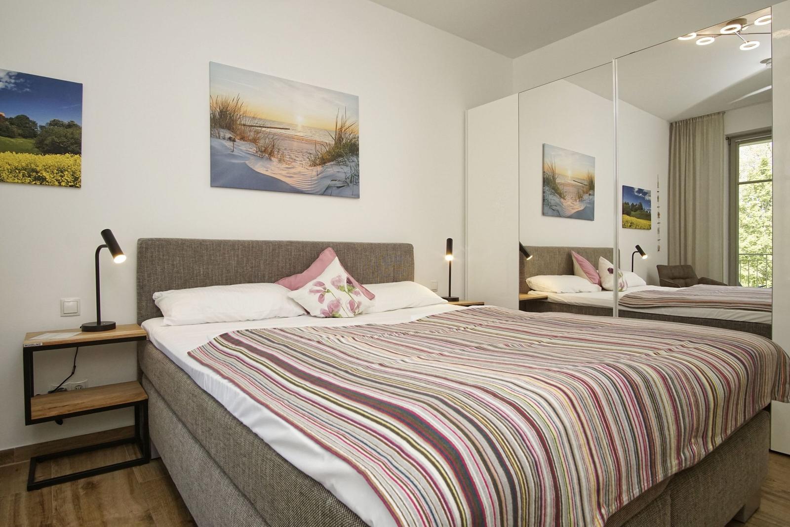 Schlafzimmer mit Bett, Nachttisch und Wandbildern