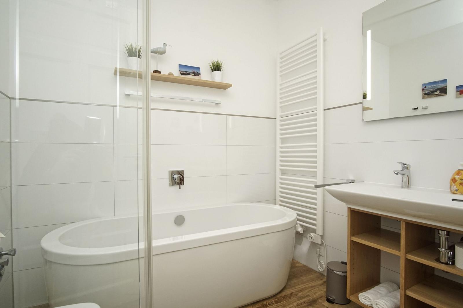 Badezimmer mit Badewanne, Duschbereich, Waschbecken und Spiegel
