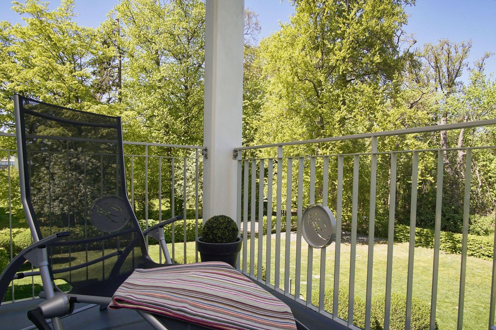Terrasse mit Liegestuhl und Blick auf grünen Garten.