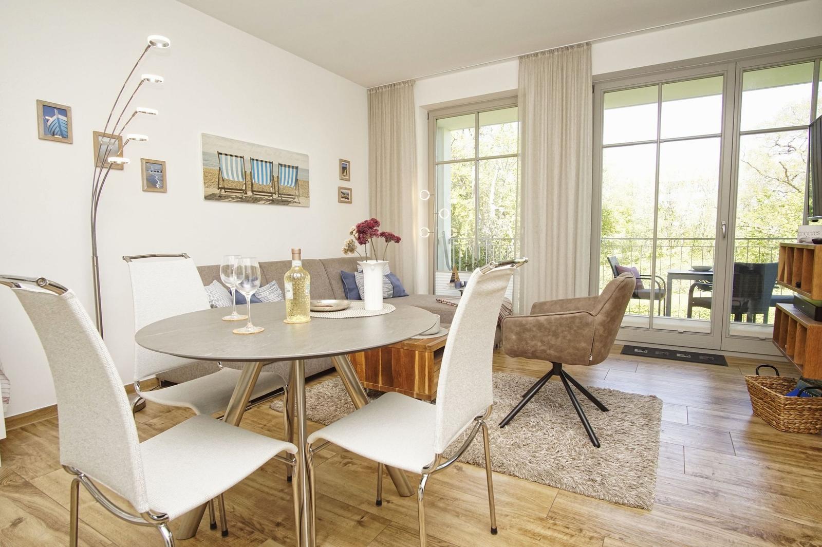 Essbereich mit runden Tisch und Stühlen, Sofa und Balkontür.