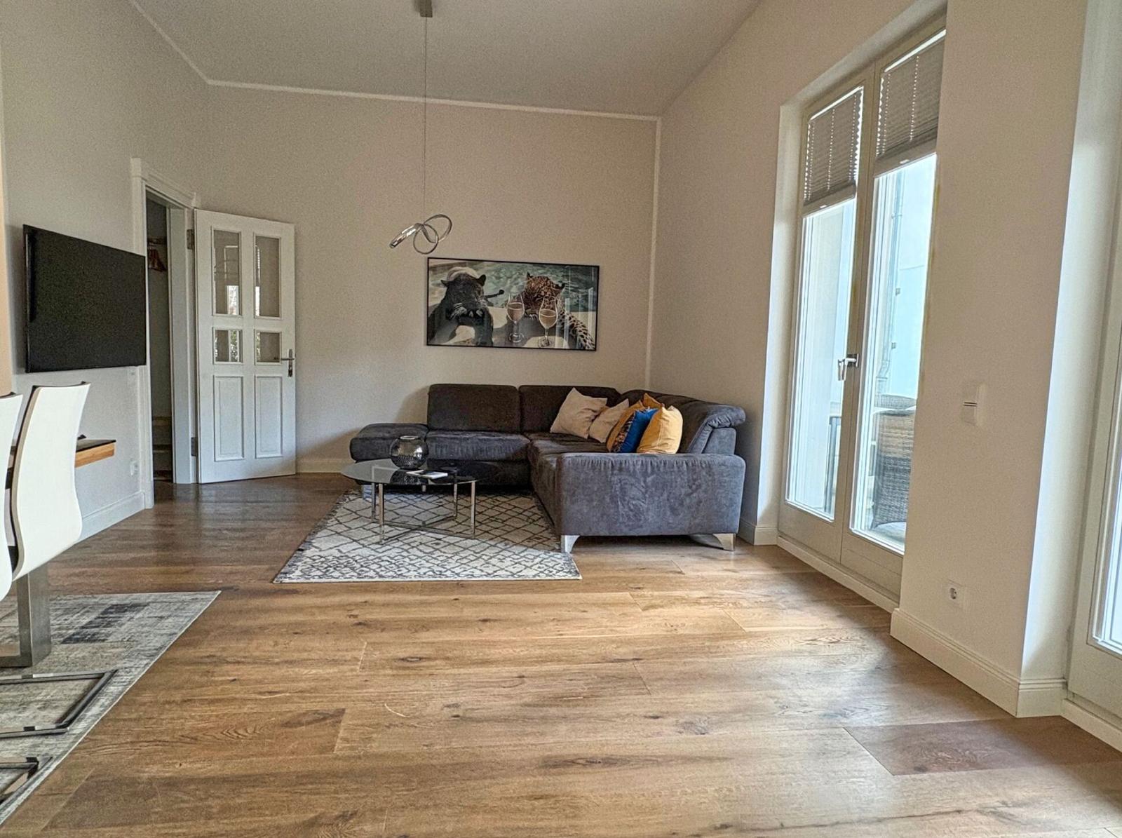 Wohnzimmer mit Sofa, Fernseher und Terrassentür.