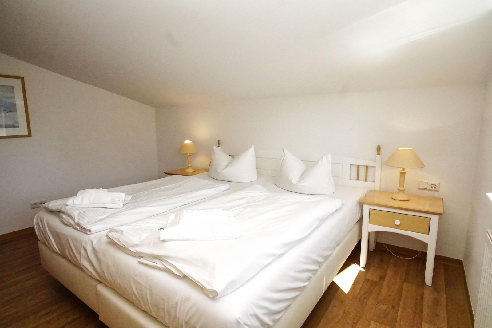 Schlafzimmer mit Doppelbett, zwei Nachttischen und Holzboden.