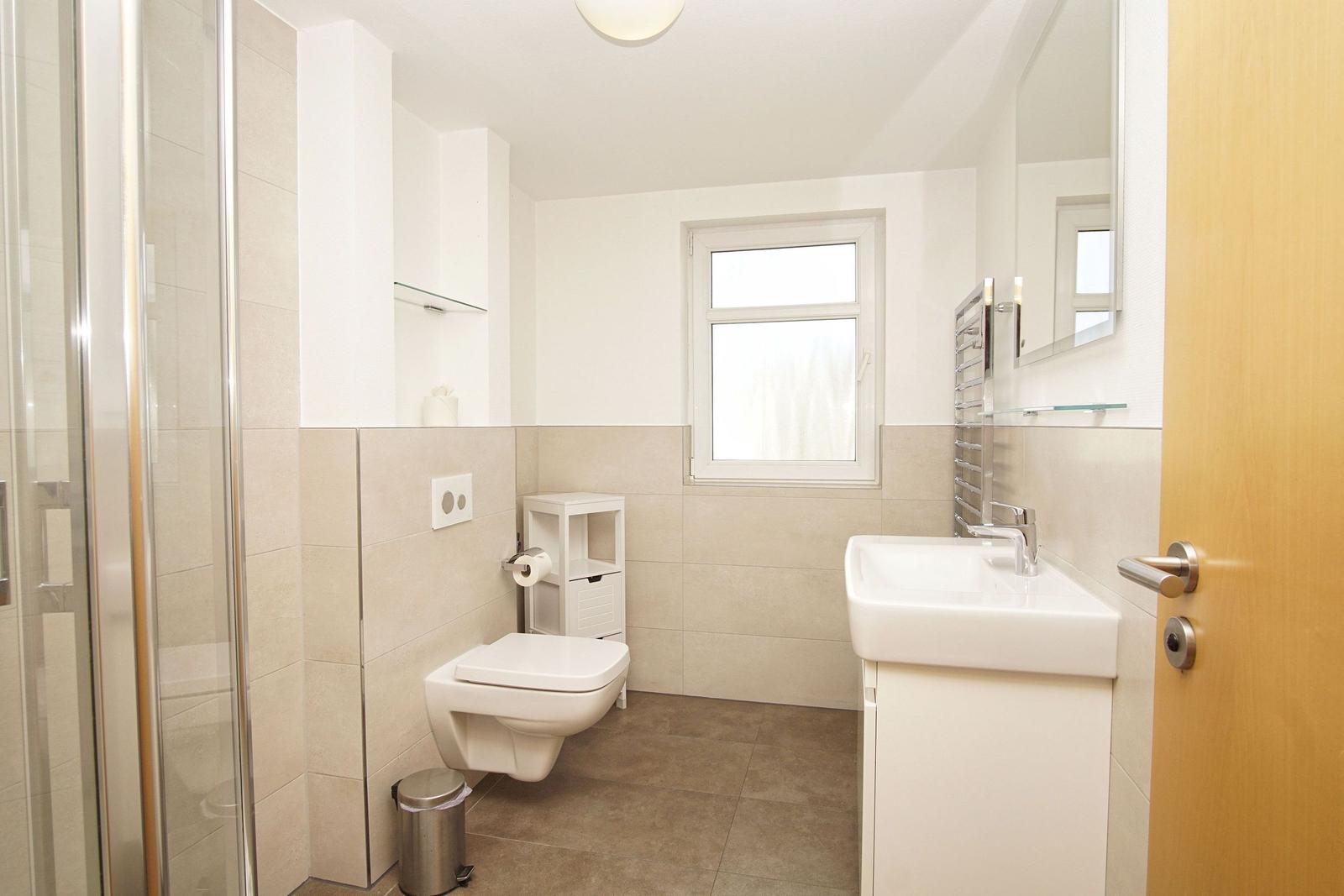 Badezimmer mit Dusche, Toilette und Waschbecken.