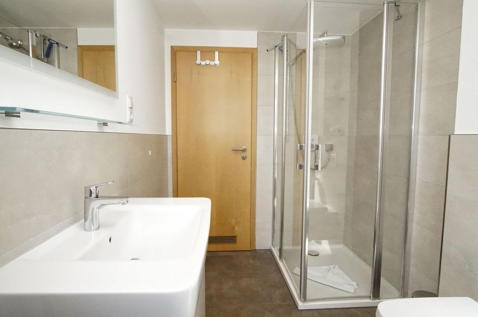 Badezimmer mit Dusche, Waschbecken und Spiegel