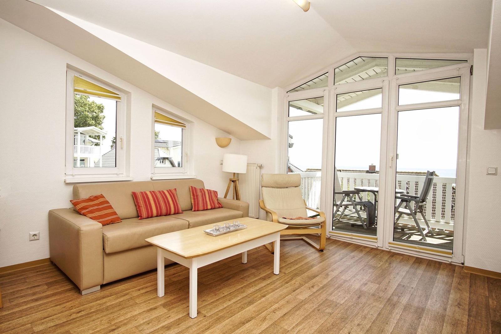 Wohnzimmer mit Sofa, Couchtisch und Balkon. Holzboden und große Fenster.