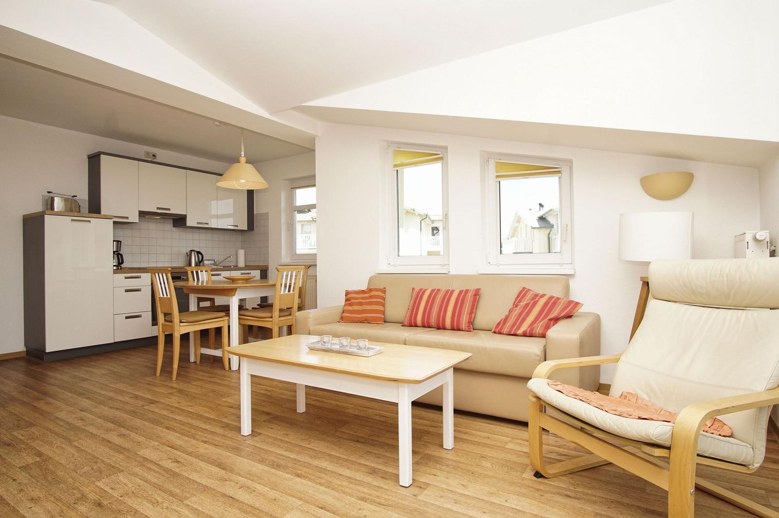 Wohn- und Küchenbereich mit Sofa, Essplatz und Holzboden.
