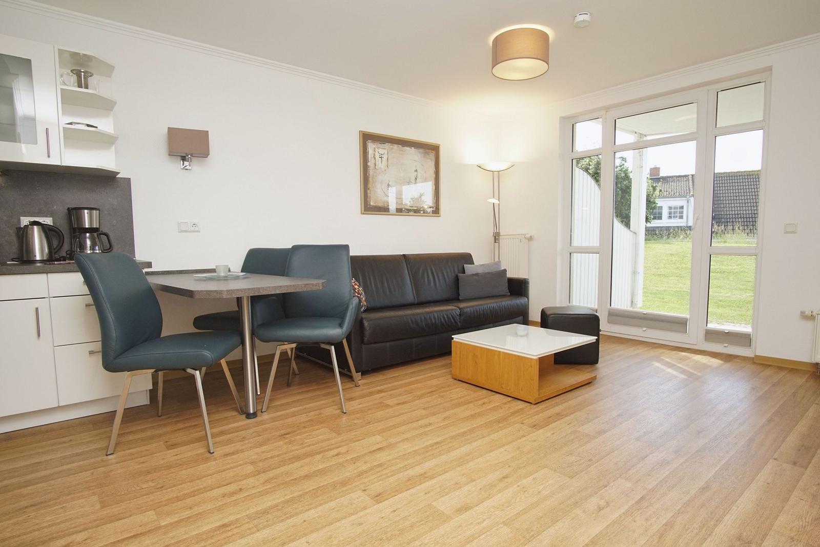 Living and dining area with sofa, table, and chairs. Door leads to the terrace.