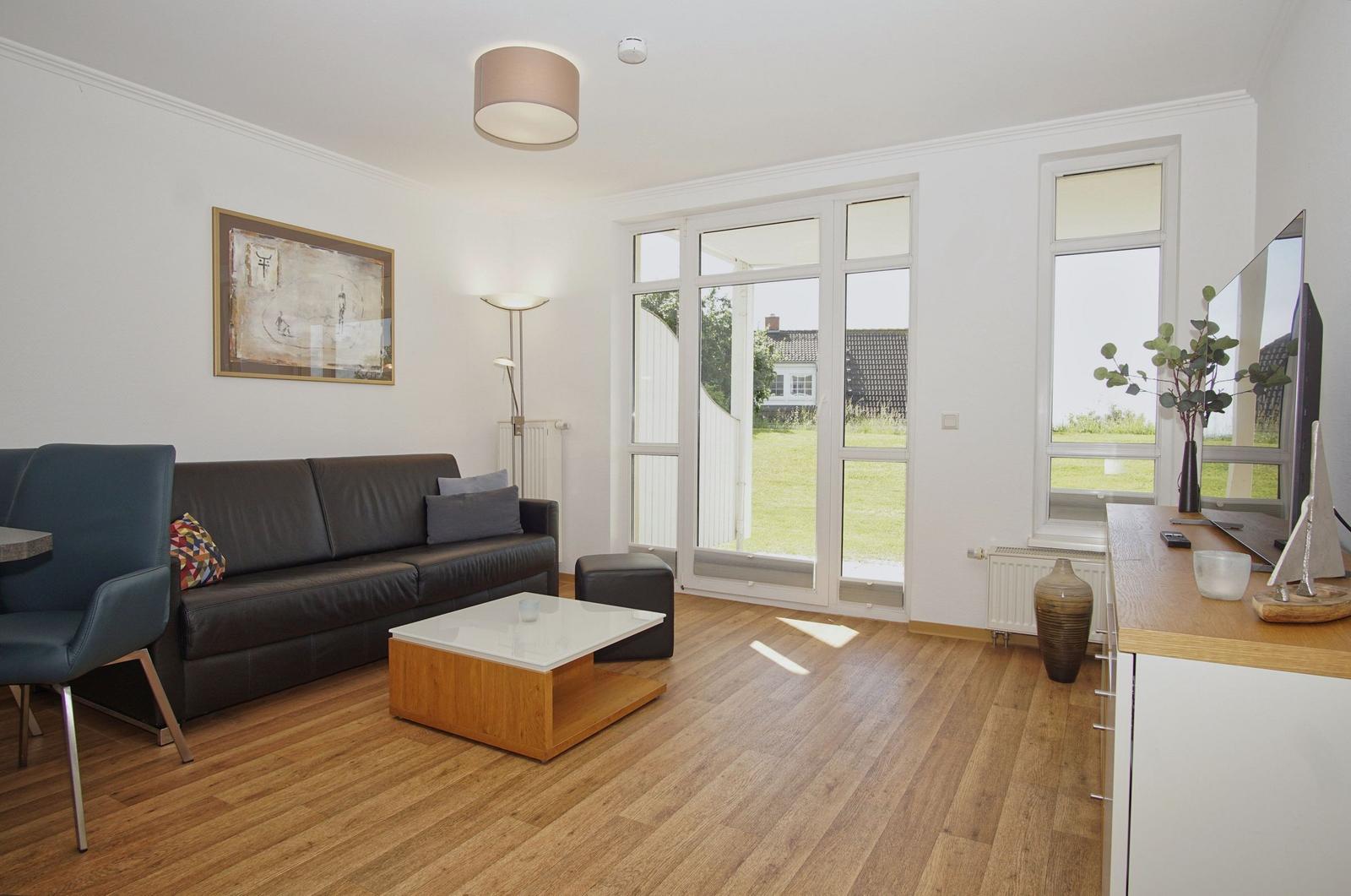 Living room with sofa, coffee table, and windows to the garden