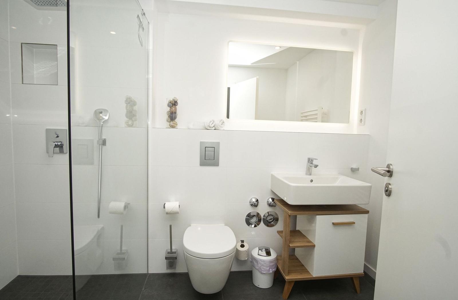 Badezimmer mit Dusche, Toilette und Waschbecken mit Spiegel.